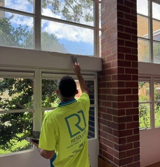 Resolute Group Painter Carefully Applying A Fresh Coat Of Paint To A Wall